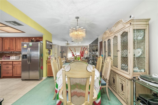 dining space featuring light tile patterned floors, visible vents, ceiling fan with notable chandelier, and a textured ceiling