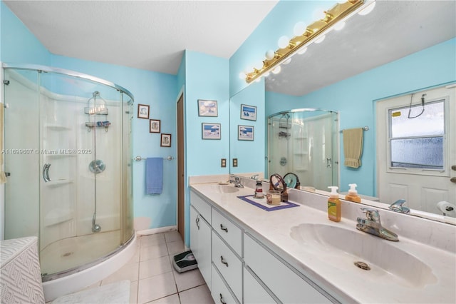 bathroom with tile patterned flooring, a shower stall, double vanity, and a sink