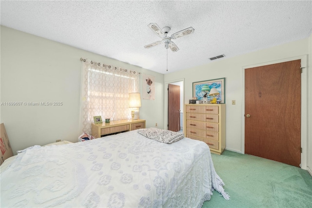 bedroom featuring a ceiling fan, light colored carpet, visible vents, and a textured ceiling