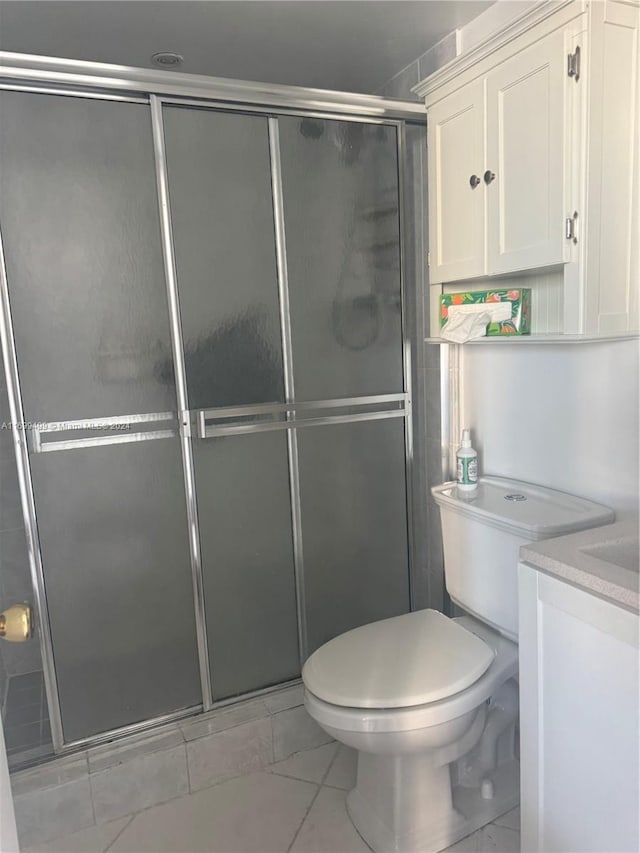 bathroom featuring vanity, toilet, and a shower with shower door