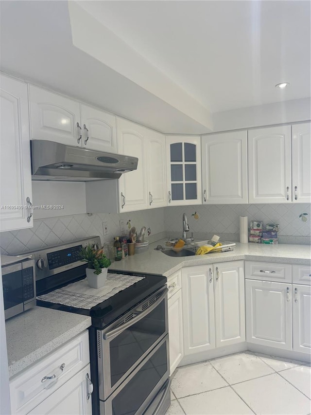 kitchen featuring decorative backsplash, light tile patterned floors, stainless steel appliances, and white cabinetry