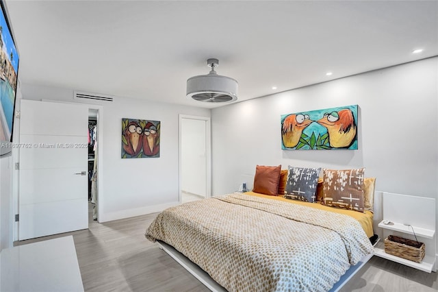 bedroom with a spacious closet, hardwood / wood-style floors, and a closet