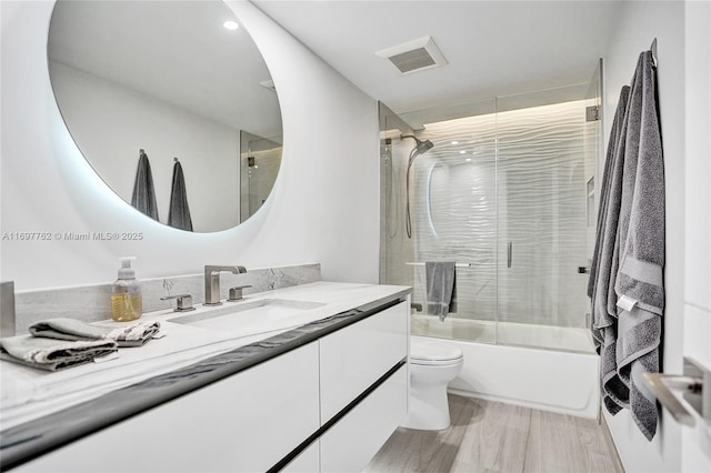 full bathroom featuring shower / bath combination with glass door, toilet, and vanity