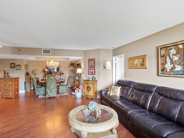 living room featuring wood-type flooring, a notable chandelier, and a textured ceiling