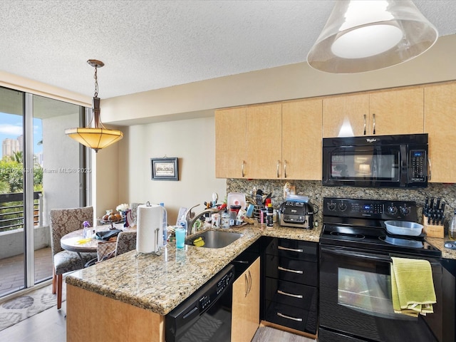 kitchen featuring black appliances, kitchen peninsula, sink, light stone countertops, and light brown cabinets