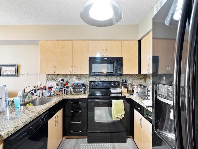 kitchen featuring backsplash, light brown cabinetry, light stone countertops, black appliances, and sink