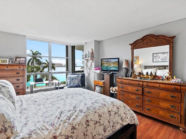 bedroom featuring a wall of windows, a textured ceiling, and light hardwood / wood-style flooring