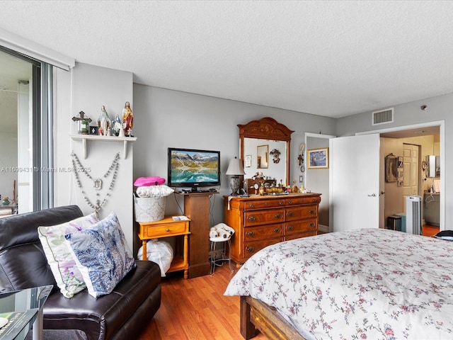 bedroom featuring a textured ceiling, ensuite bathroom, and wood-type flooring