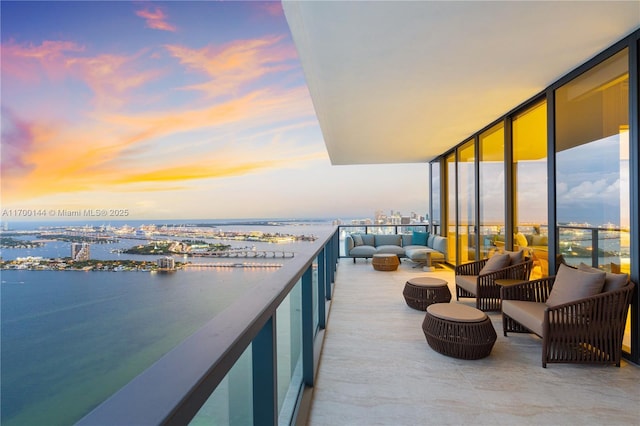 balcony at dusk with a water view and an outdoor living space