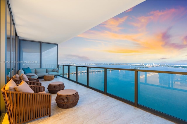 balcony at dusk featuring a water view and outdoor lounge area