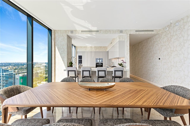 dining space with floor to ceiling windows, visible vents, and wallpapered walls