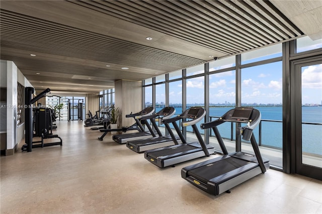 workout area featuring a water view and expansive windows