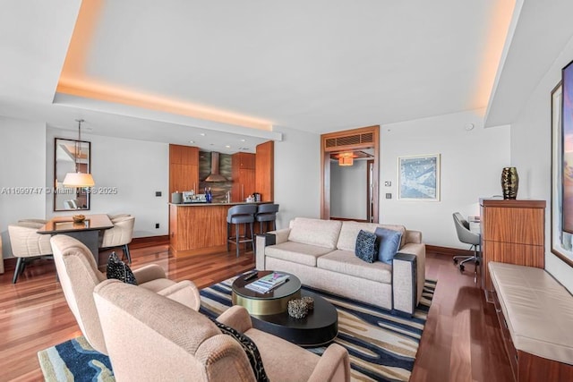 living room with light wood-type flooring and a tray ceiling