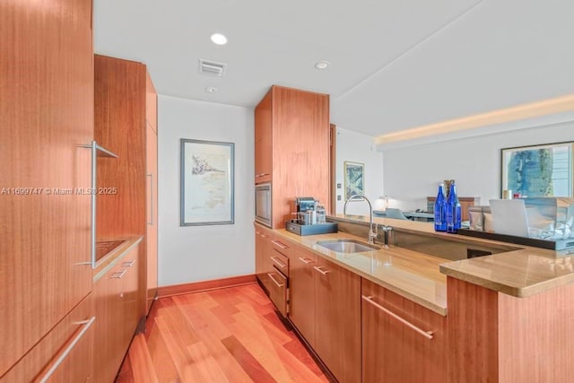 kitchen featuring kitchen peninsula, sink, oven, and light hardwood / wood-style flooring