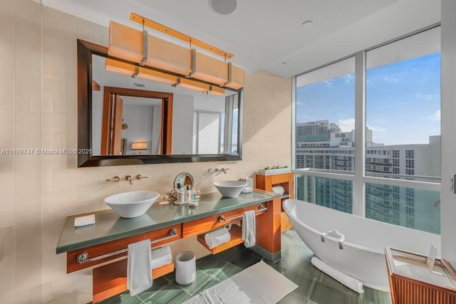 bathroom with floor to ceiling windows, a washtub, tasteful backsplash, tile patterned floors, and vanity