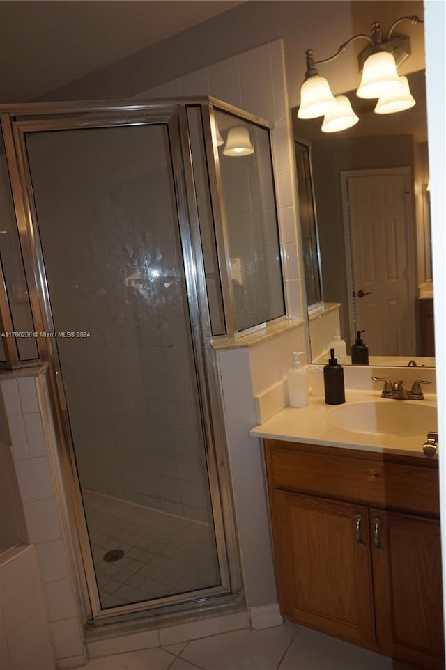 bathroom with tile patterned flooring, vanity, and walk in shower