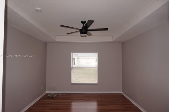 unfurnished room featuring a textured ceiling, dark hardwood / wood-style floors, ceiling fan, and a tray ceiling