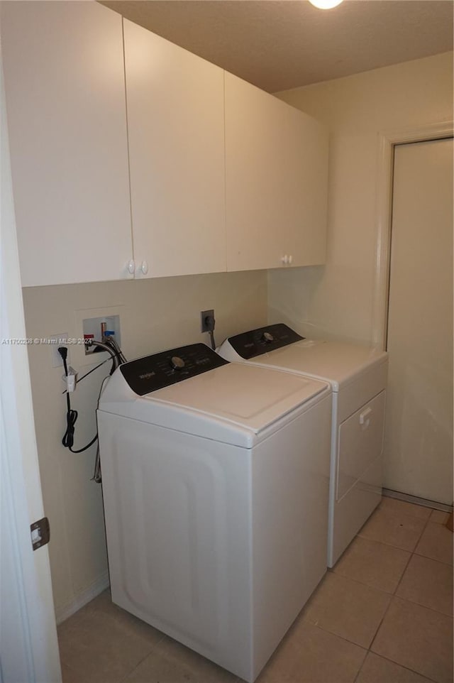 laundry area featuring cabinets, light tile patterned floors, and washer and dryer