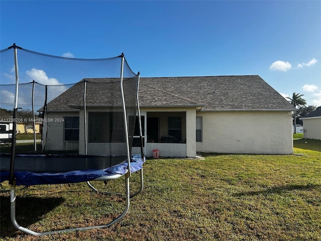 back of house with a lawn and a trampoline