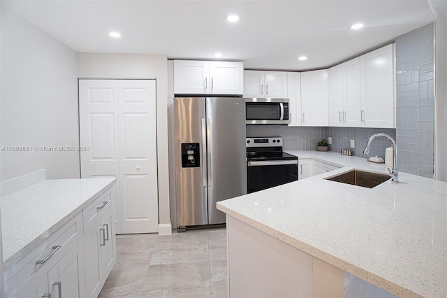 kitchen with white cabinets, light stone counters, sink, and stainless steel appliances