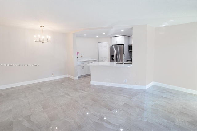 unfurnished living room featuring a notable chandelier and sink