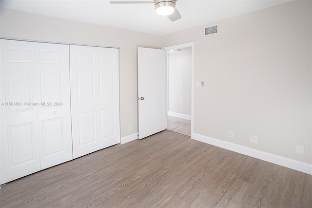 unfurnished bedroom with light wood-type flooring, a closet, and ceiling fan