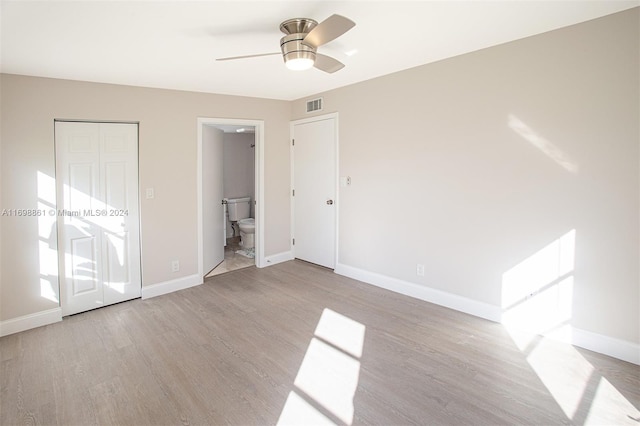 unfurnished bedroom featuring a closet, ensuite bathroom, light hardwood / wood-style flooring, and ceiling fan