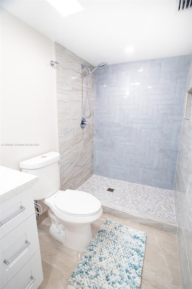 bathroom featuring vanity, toilet, and a tile shower