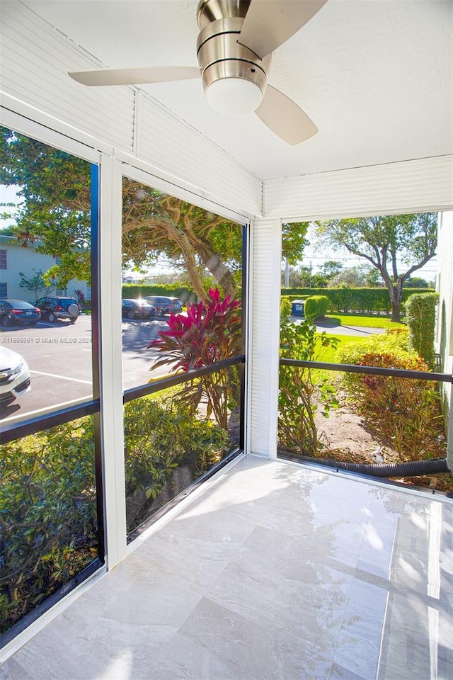 unfurnished sunroom featuring ceiling fan