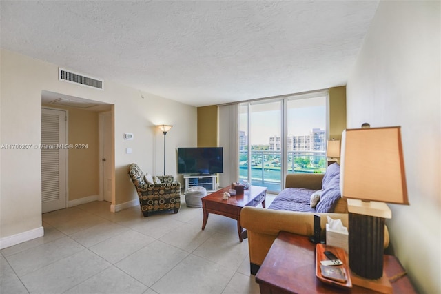 living room featuring a textured ceiling, a wall of windows, and light tile patterned flooring