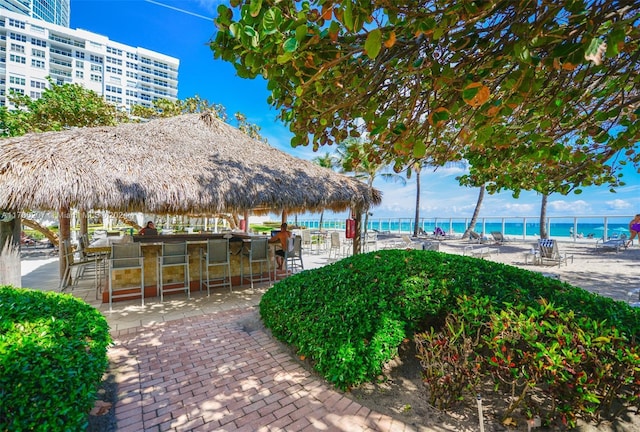 view of patio featuring a water view, a bar, and a gazebo