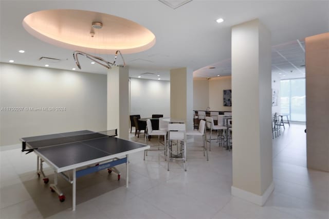 recreation room featuring a raised ceiling and light tile patterned flooring