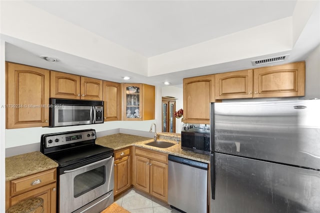 7690 NW 18th St Unit 408, Margate, FL 33063 - kitchen with appliances with stainless steel finishes, light stone counters, glass insert cabinets, light tile patterned floors, and brown cabinetry