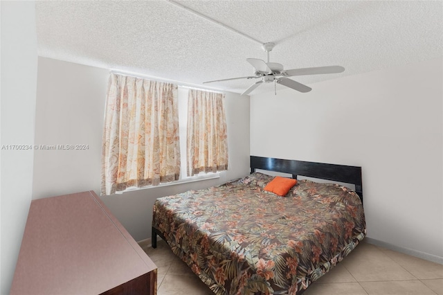 bedroom with ceiling fan, light tile patterned floors, and a textured ceiling