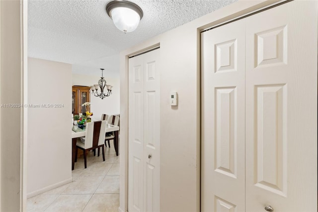 hallway with a chandelier, light tile patterned floors, and a textured ceiling