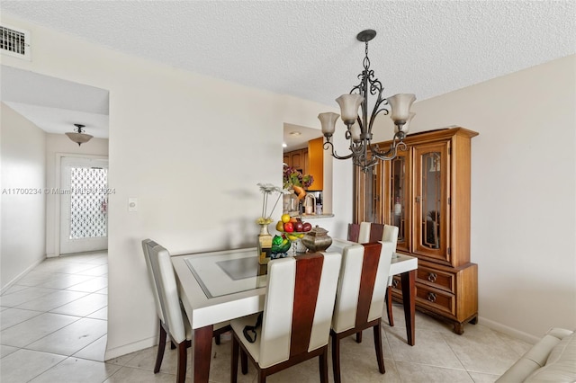 tiled dining area featuring a chandelier and a textured ceiling