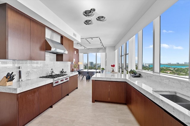 kitchen featuring tasteful backsplash, plenty of natural light, wall chimney range hood, and stainless steel gas cooktop