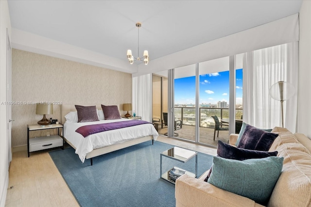 bedroom featuring an inviting chandelier, access to exterior, and light hardwood / wood-style flooring