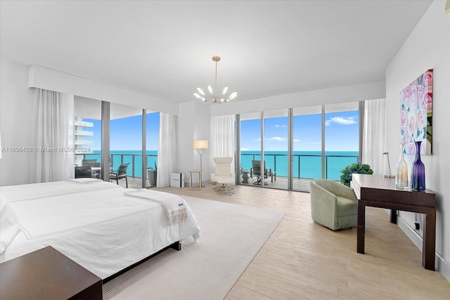 bedroom featuring a notable chandelier, a water view, light wood-type flooring, and access to outside