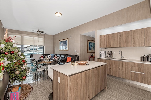 kitchen with ceiling fan, sink, a center island, and light tile patterned floors