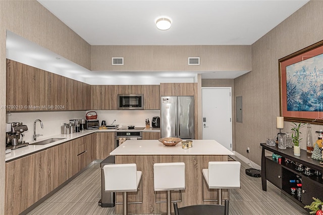 kitchen featuring sink, a kitchen breakfast bar, electric panel, a kitchen island, and appliances with stainless steel finishes