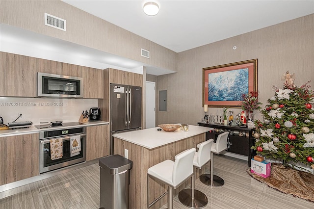 kitchen featuring a kitchen breakfast bar, a center island, stainless steel appliances, and electric panel