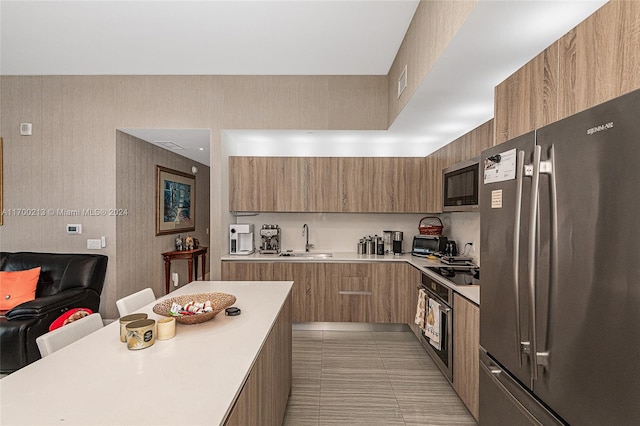 kitchen with light tile patterned flooring, appliances with stainless steel finishes, a kitchen bar, and sink