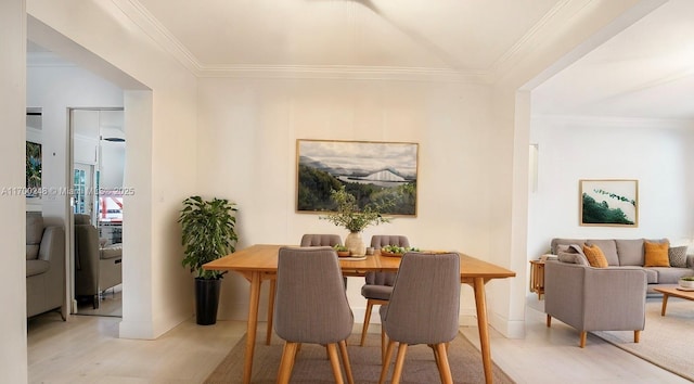 dining room with light wood-style floors, baseboards, and ornamental molding