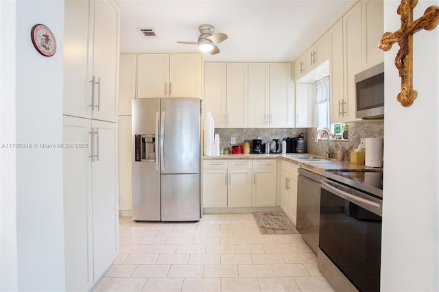 kitchen featuring visible vents, decorative backsplash, ceiling fan, appliances with stainless steel finishes, and a sink