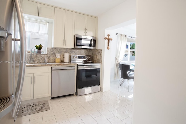 kitchen featuring decorative backsplash, appliances with stainless steel finishes, light countertops, a sink, and light tile patterned flooring