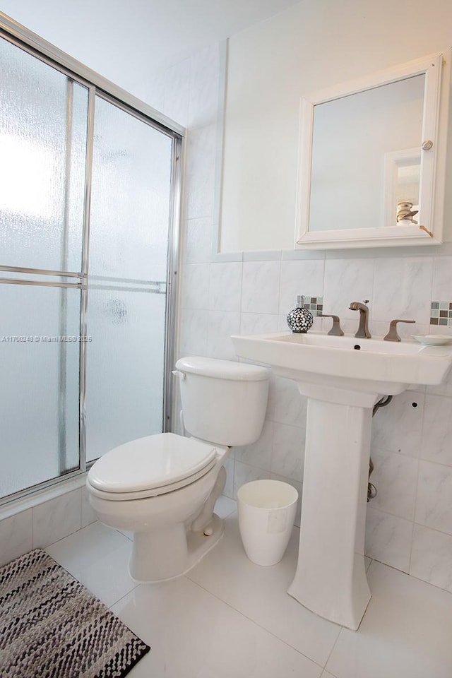 full bathroom featuring toilet, a shower stall, tile walls, and tile patterned floors