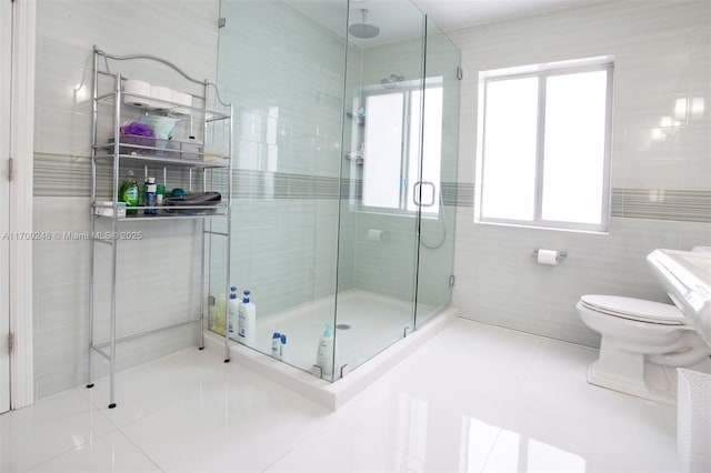 bathroom with a stall shower, tile walls, toilet, and tile patterned floors