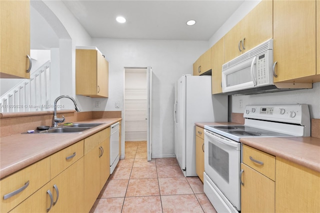 kitchen featuring light brown cabinetry, sink, light tile patterned floors, and white appliances