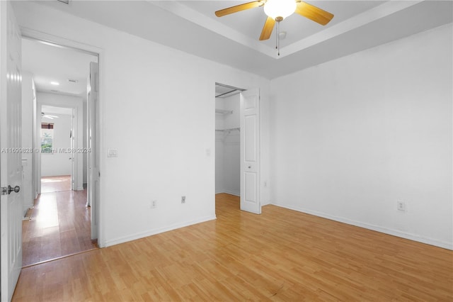 unfurnished bedroom featuring ceiling fan, a closet, a spacious closet, and light wood-type flooring